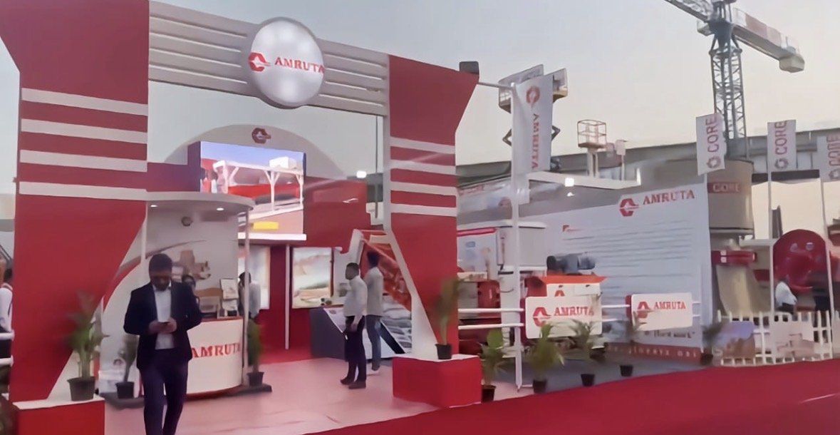 Side view of the Amruta stall showing the arch, curved counter, screen and flag banners
