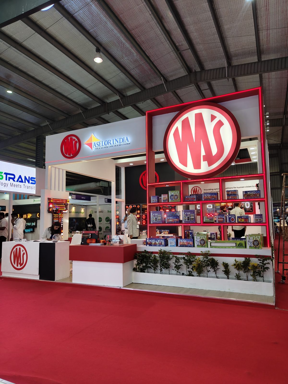 Backlit WAS logo above the red shelving wall at the Aselor India stall
