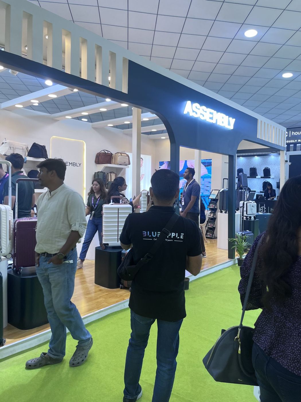 Navy arch with backlit Assembly letters and visitors at the stall entrance