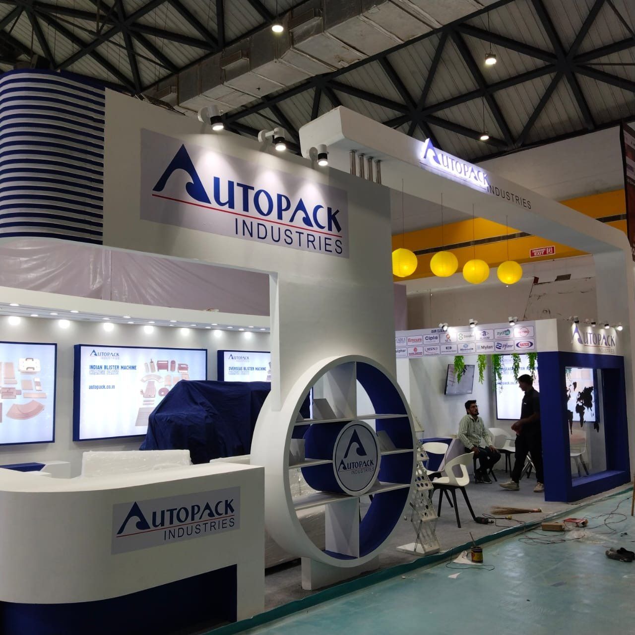 Autopack stall front with circular logo shelf, portal fascia and meeting area with yellow pendant lamps
