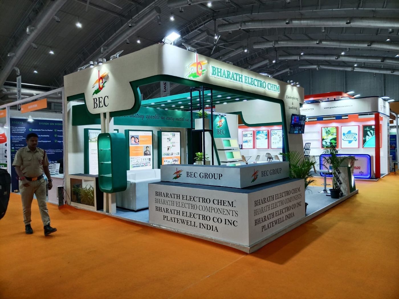 BEC stall with rounded logo panel, green capsule shelf, lounge sofa and two-tier counter