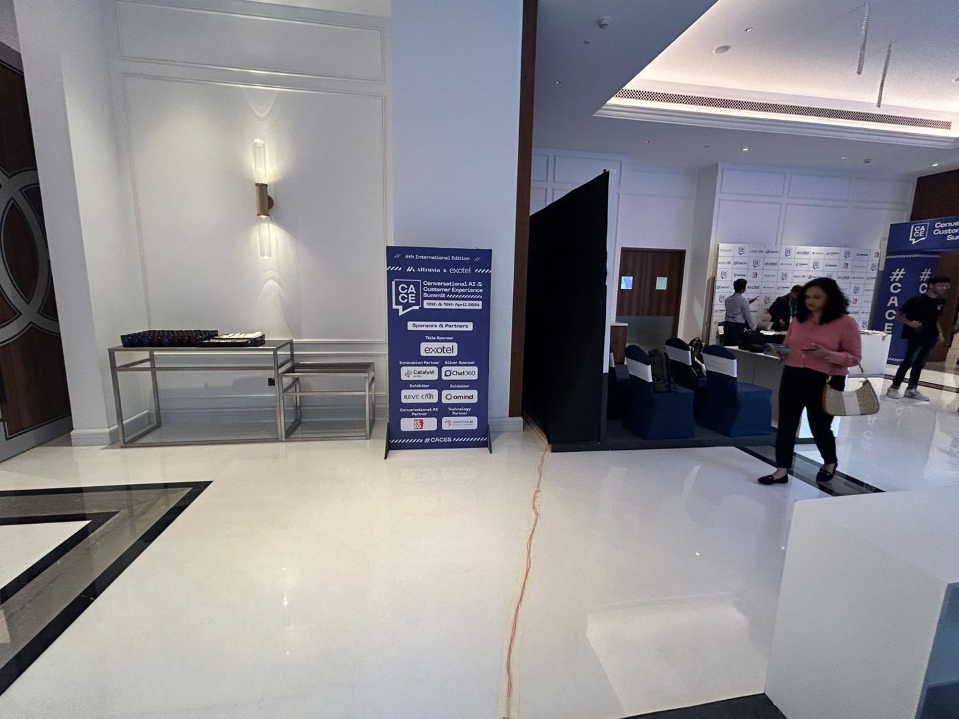 CACES sponsors standee in the hotel corridor next to a black draped seating enclosure
