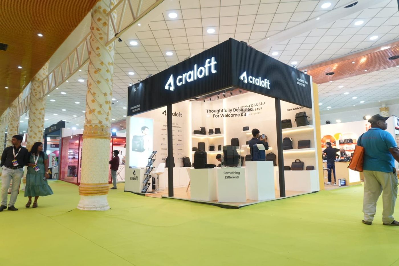 Wide view of the Craloft stall with its black fascia, lit shelving and white plinths on a timber-look floor