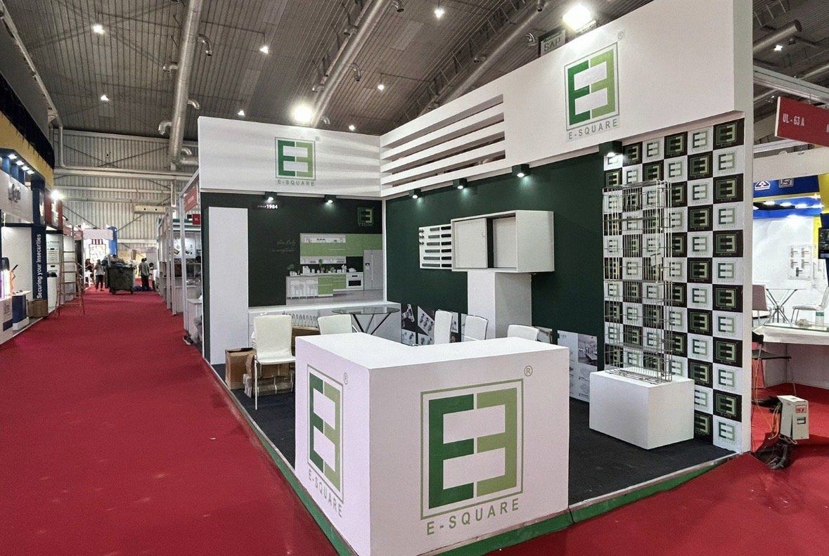 E-Square corner stall with white fascia, dark green walls, a checked logo tile wall and a white branded counter