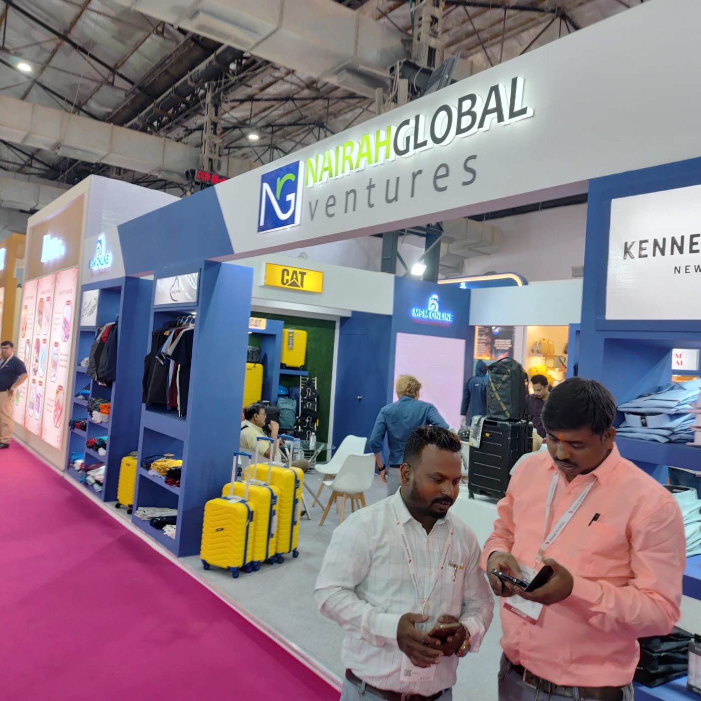 Blue display bays with jackets, folded shirts and a CAT luggage bay with yellow suitcases