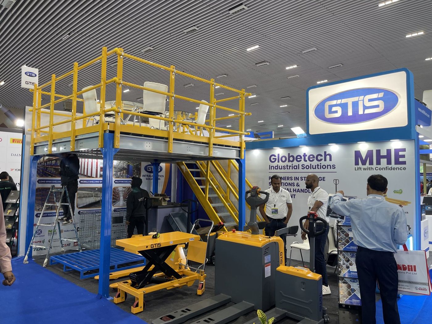 GTIS backlit logo header beside the steel deck with yellow railings and a scissor lift table