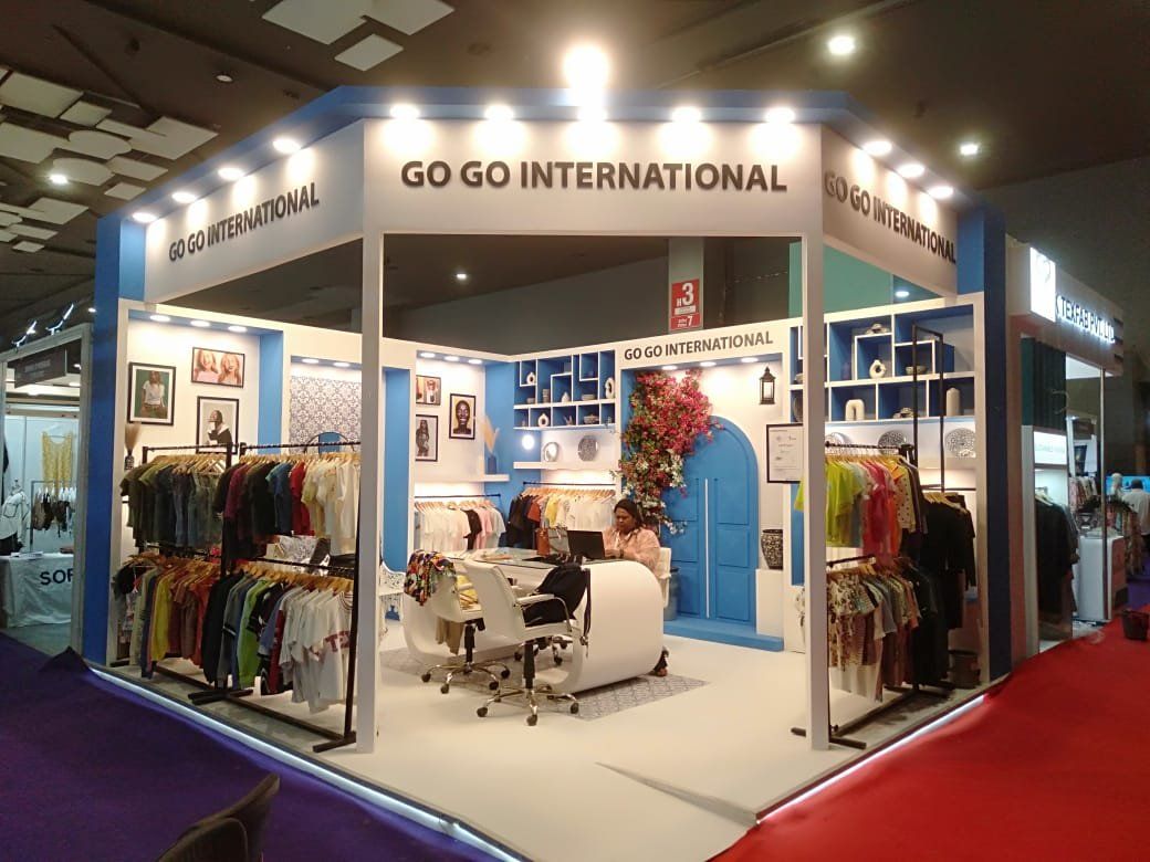 Go Go International blue and white stall with lettered fascia, blue niches, arched door feature and garment rails