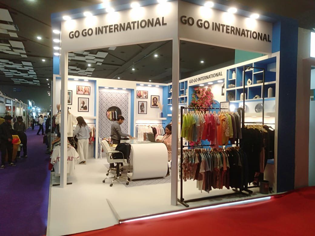 Corner view of Go Go International stall with garment rails, blue shelving and bougainvillea