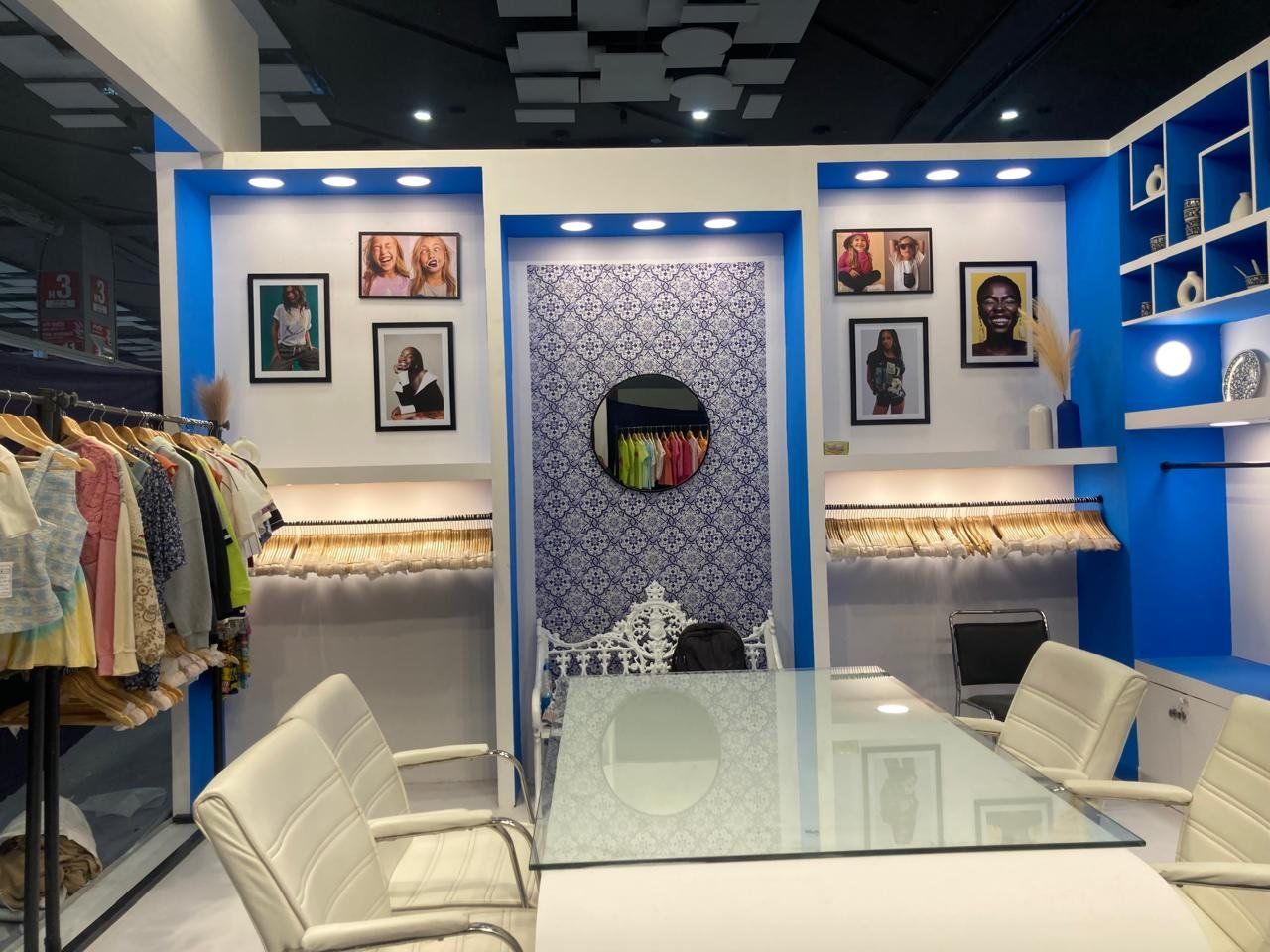 Back wall with framed portraits, hanging rails, tile pattern niche and white meeting table