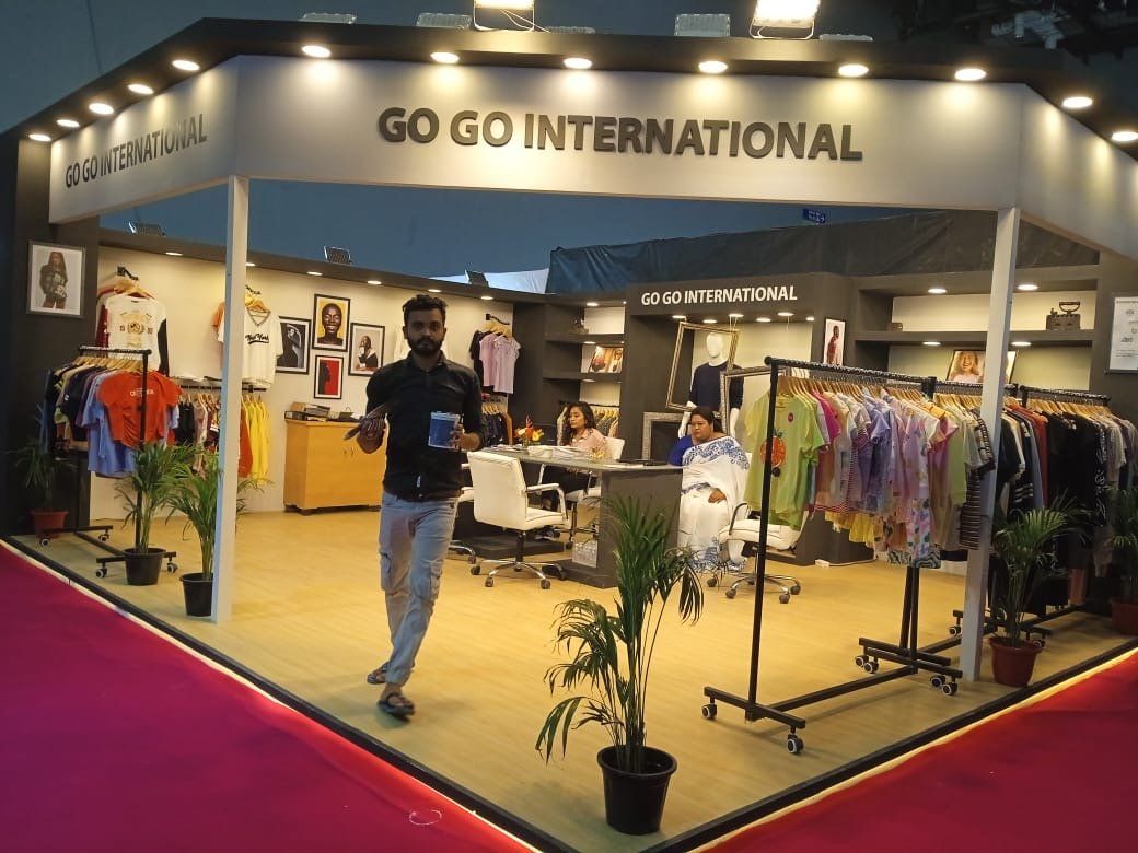 Go Go International stall interior with garment rails, grey shelving, mannequin and white chairs