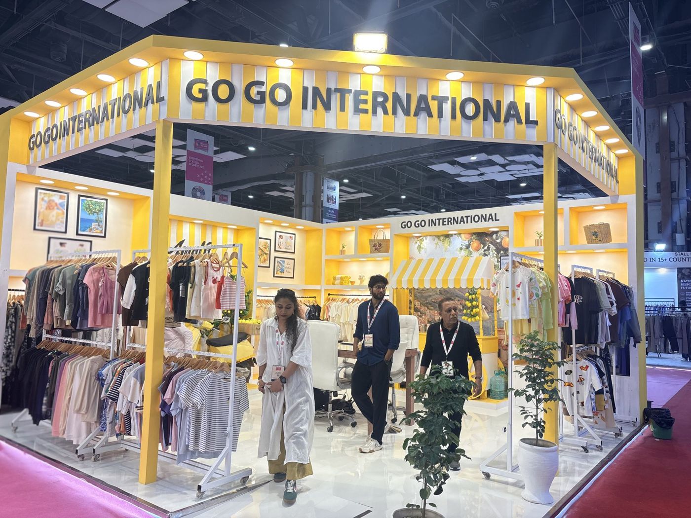 Go Go International stall with yellow columns, lit niches, striped awning cart and meeting area