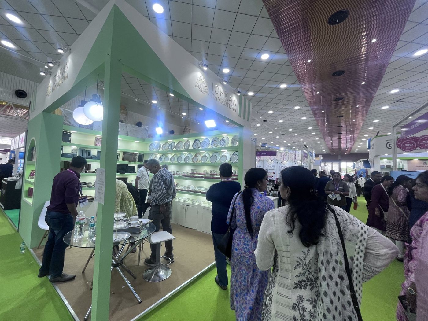Mint green gabled stall with lit shelving full of decorated plates, arched niche and glass table