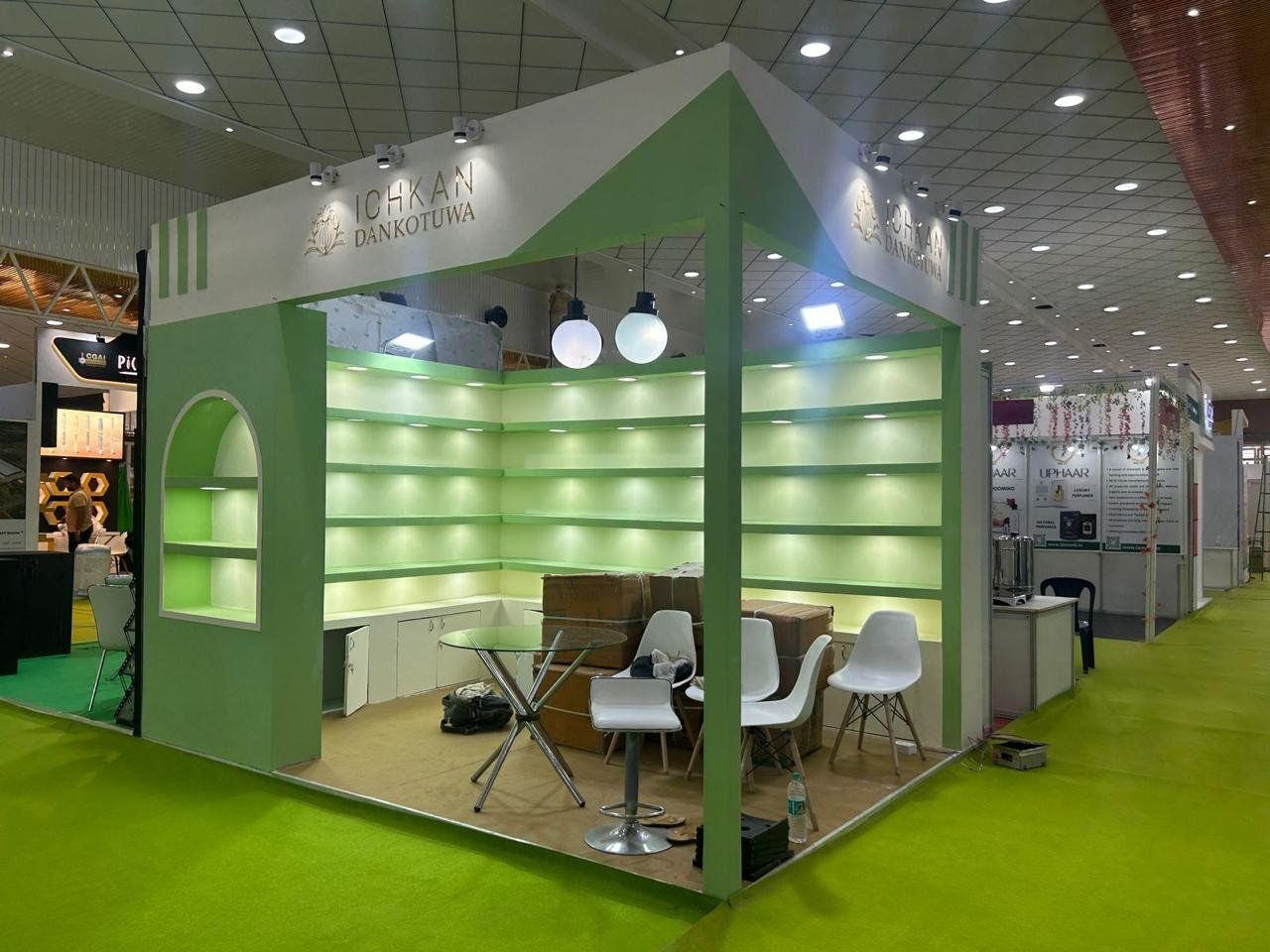 Empty green stall after installation with lit L-shaped shelving and stock cartons