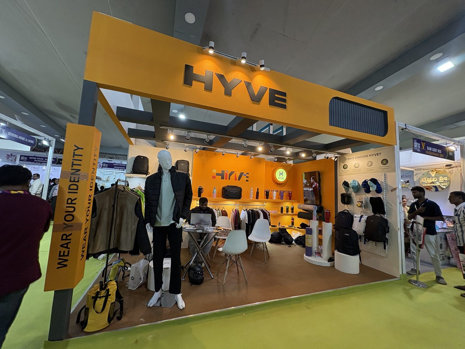 Hyve corner stall with orange fascia, grey posts, hanging rails and bags on shelves