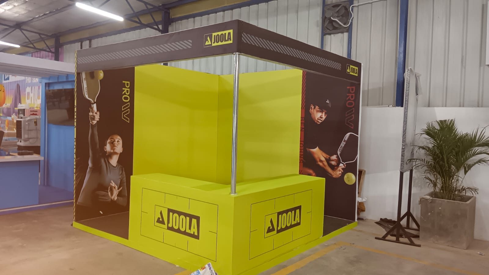 JOOLA compact stall with yellow walls, player graphics and branded corner counter