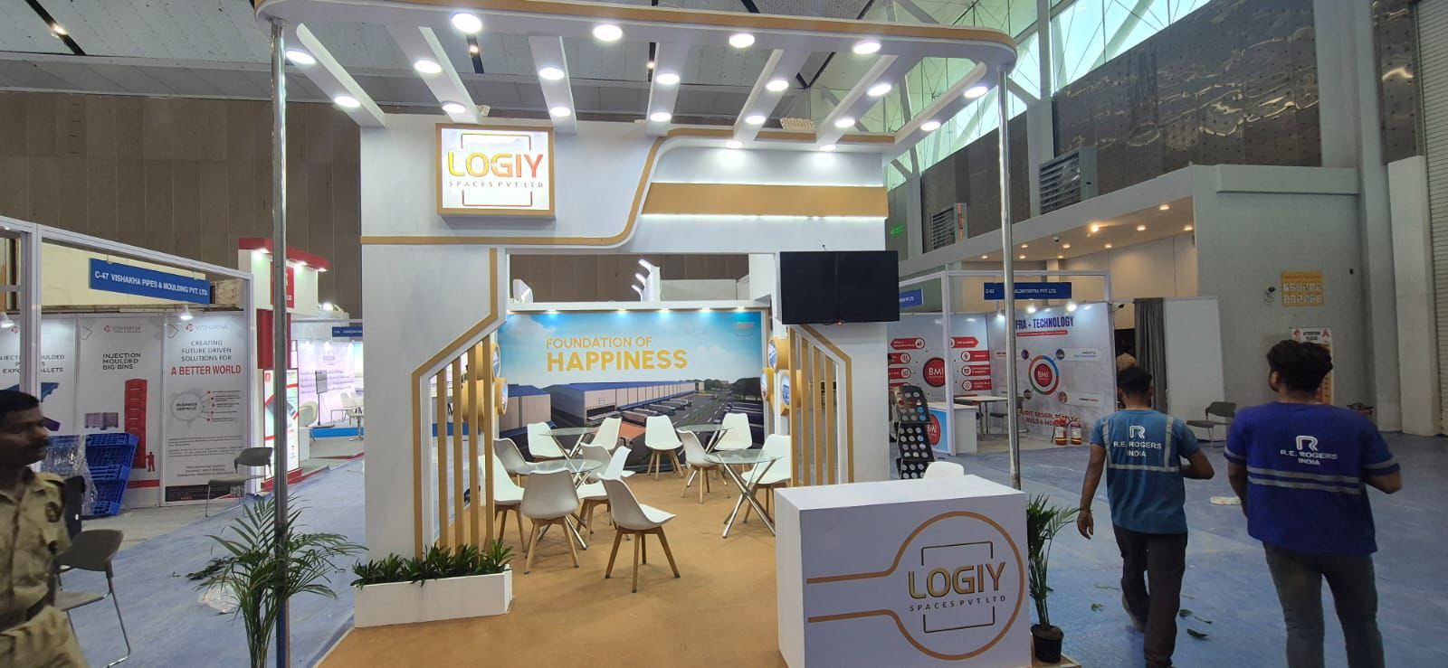 Logiy Spaces stall with lit frame, gold slat columns, lounge and branded counter