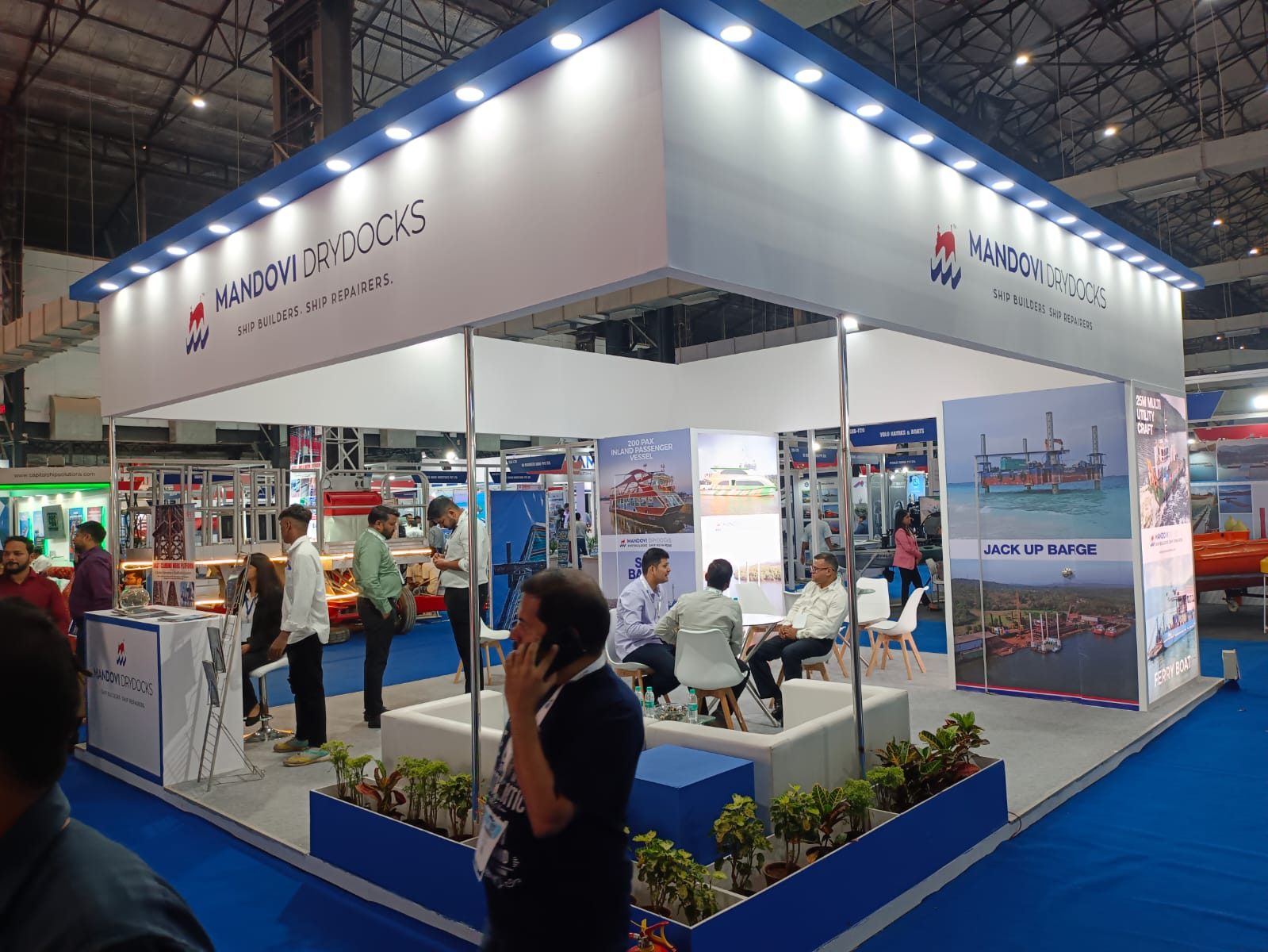 Mandovi Drydocks open stall with lit fascia, vessel panels, planters and lounge