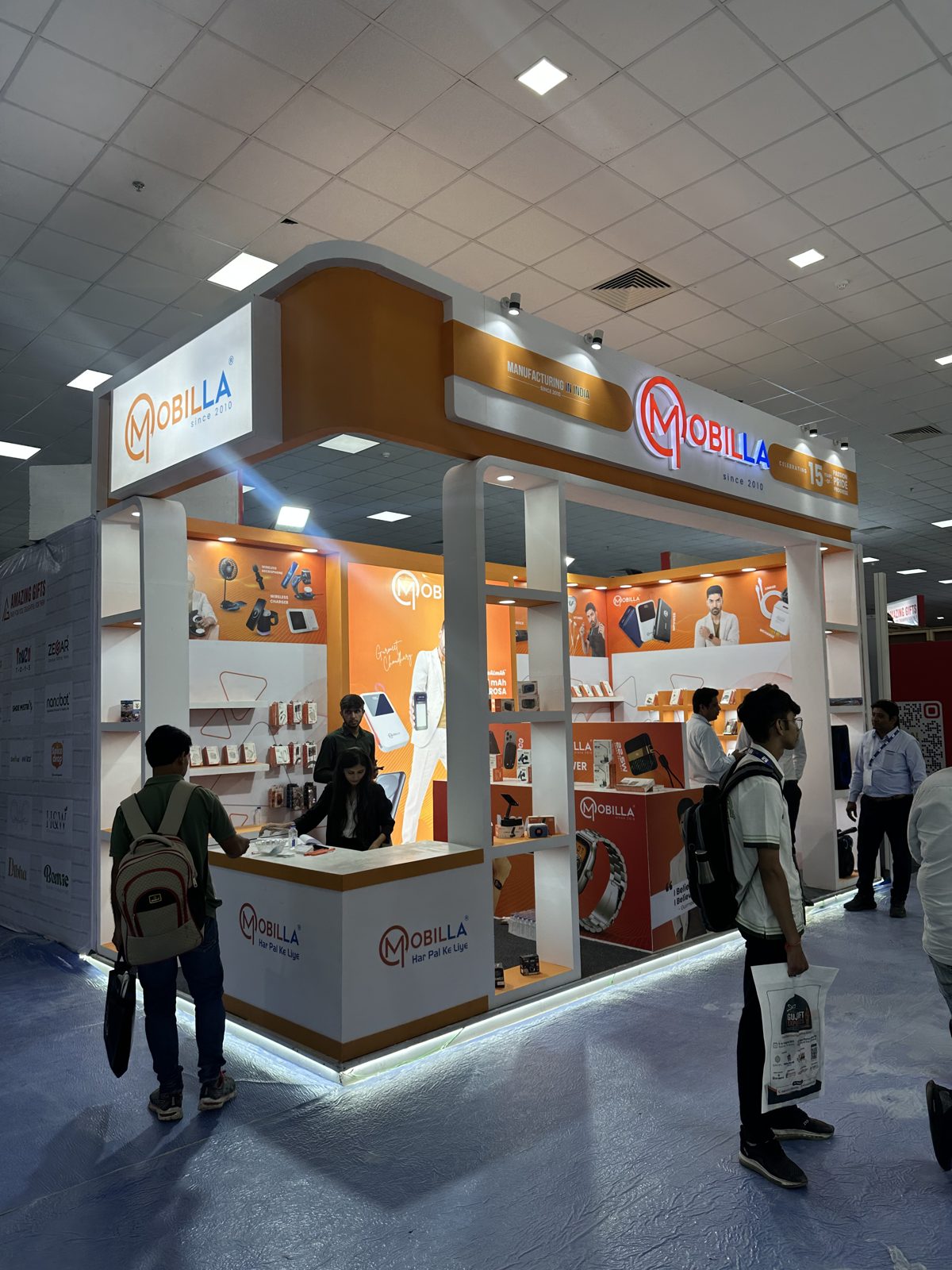 Mobilla corner stall with curved orange fascia, lit shelving and branded counter