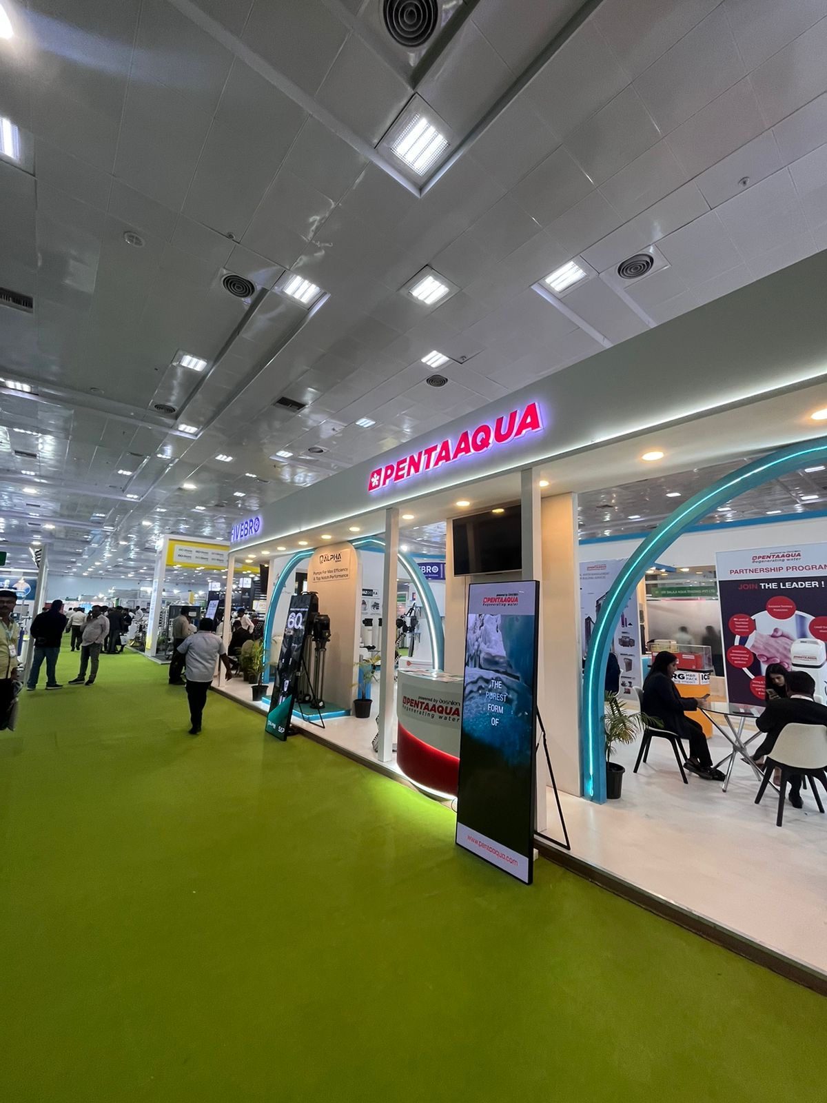 Pentaaqua stall with backlit pink logo, teal LED arch and digital standee
