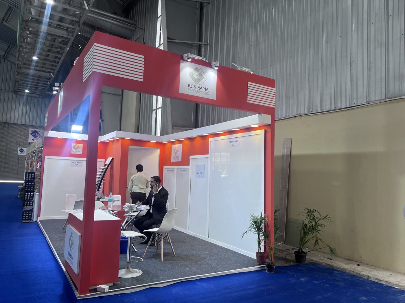 Red corner stall with white framed quartz slab panels, warm downlights and meeting tables