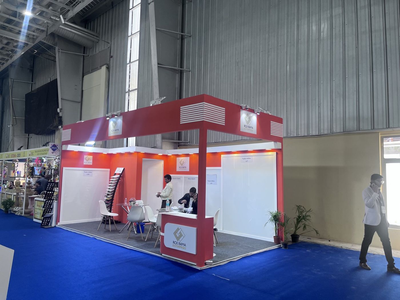 Red and white corner stall with logo panels, warm downlights and labelled slab displays