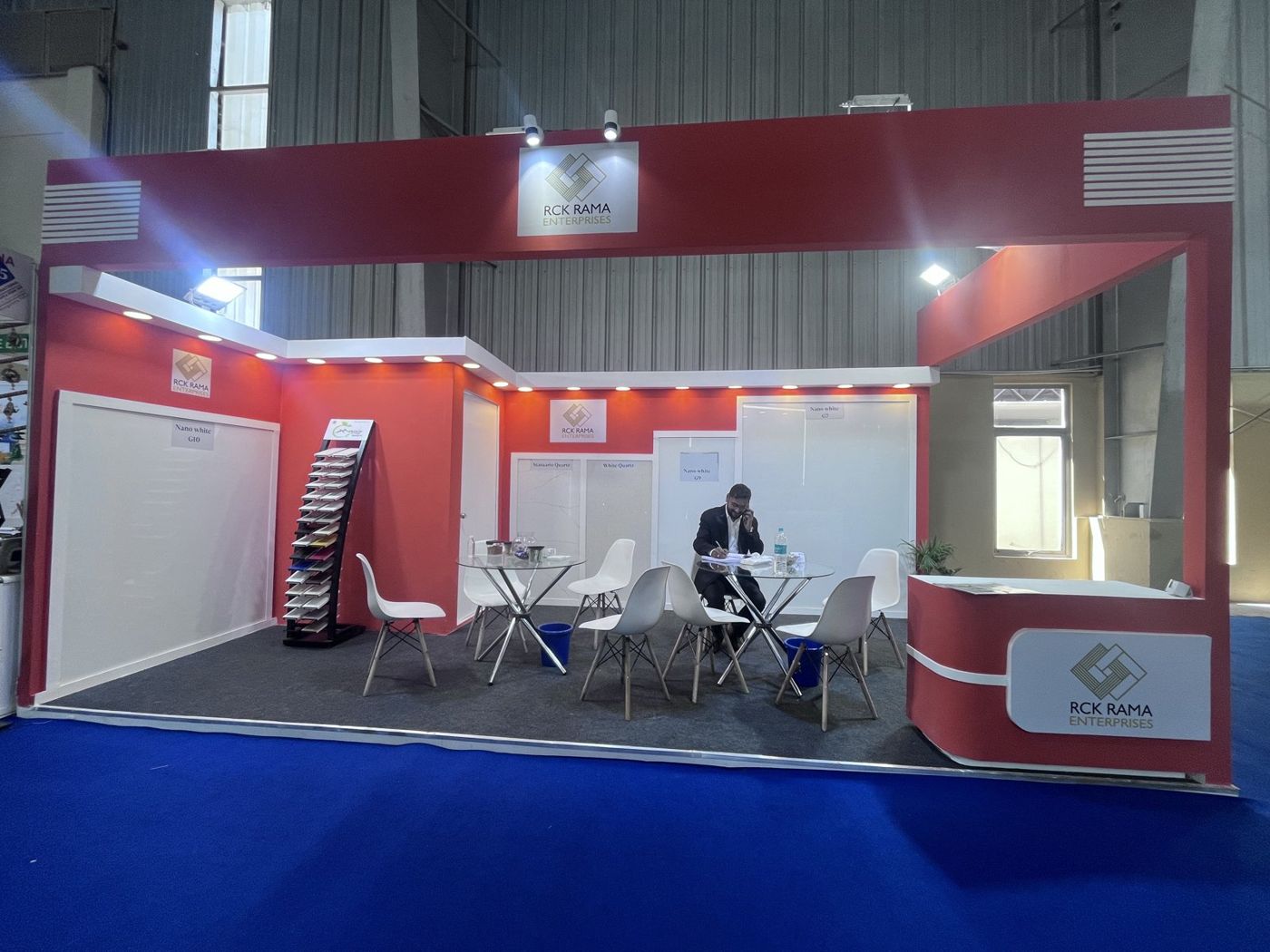 Front of the red stall with slab panels, sample rack, glass meeting tables and red reception counter