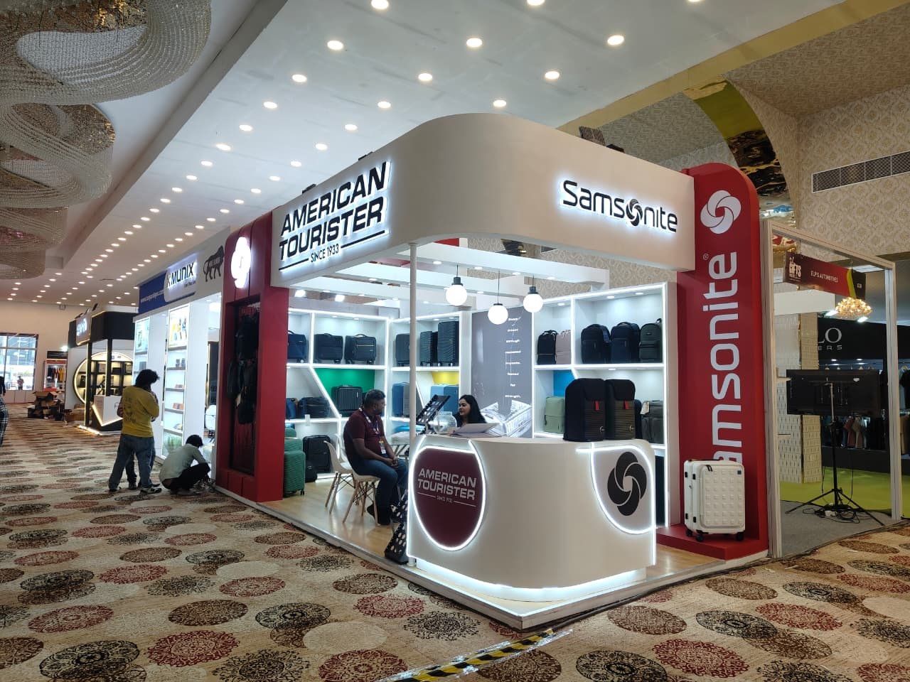 Samsonite and American Tourister corner stall with backlit fascia, red towers and LED-ringed counter