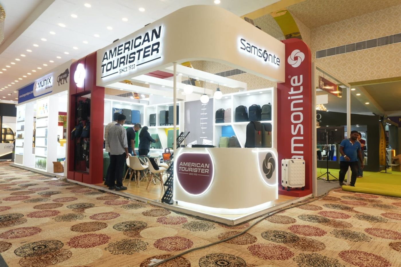 Front of the corner stall with curved counter, globe pendants and lit shelving with bags