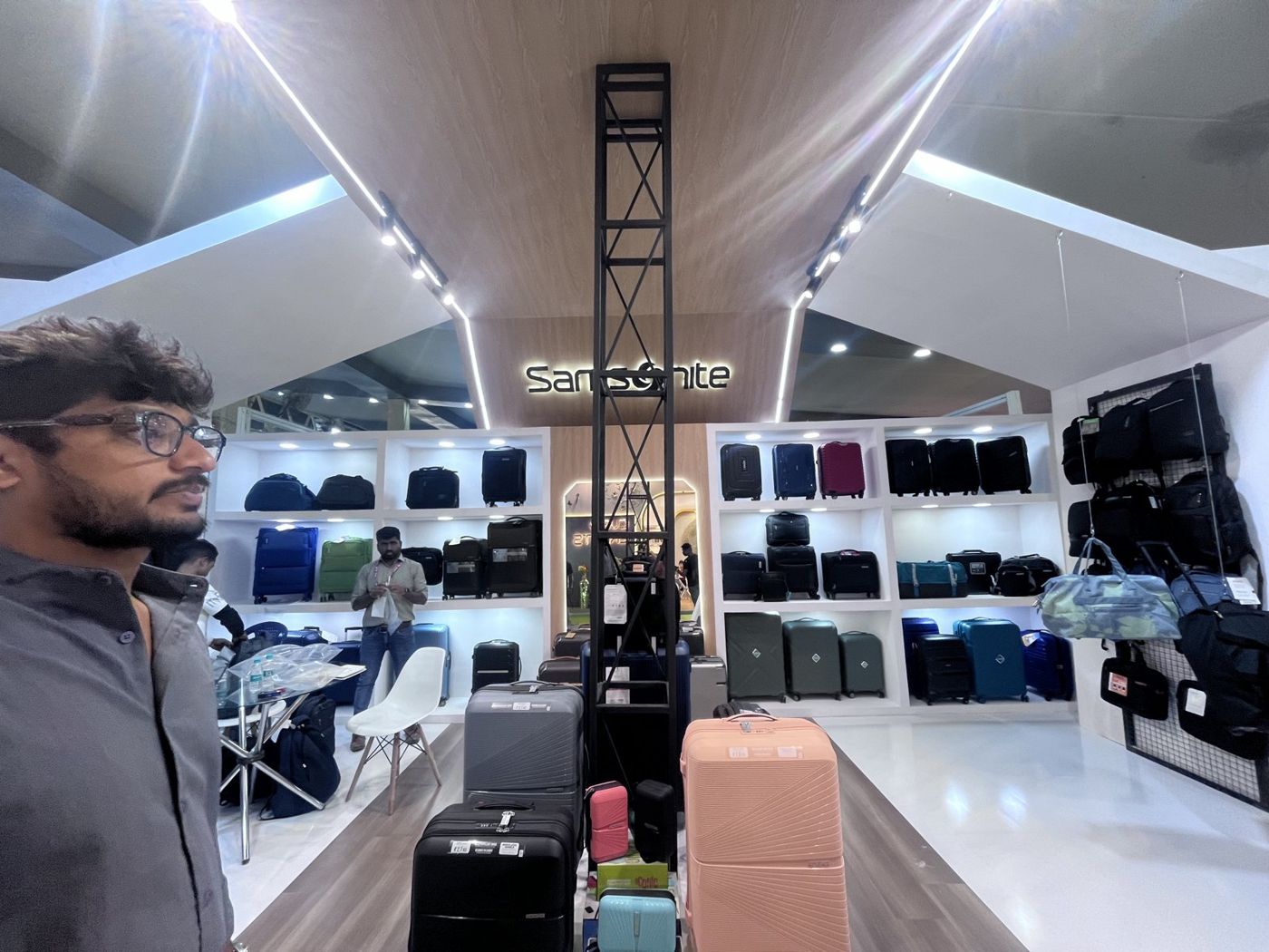 Lit white shelving with suitcases and bags, backlit Samsonite logo and featured cases on a plinth
