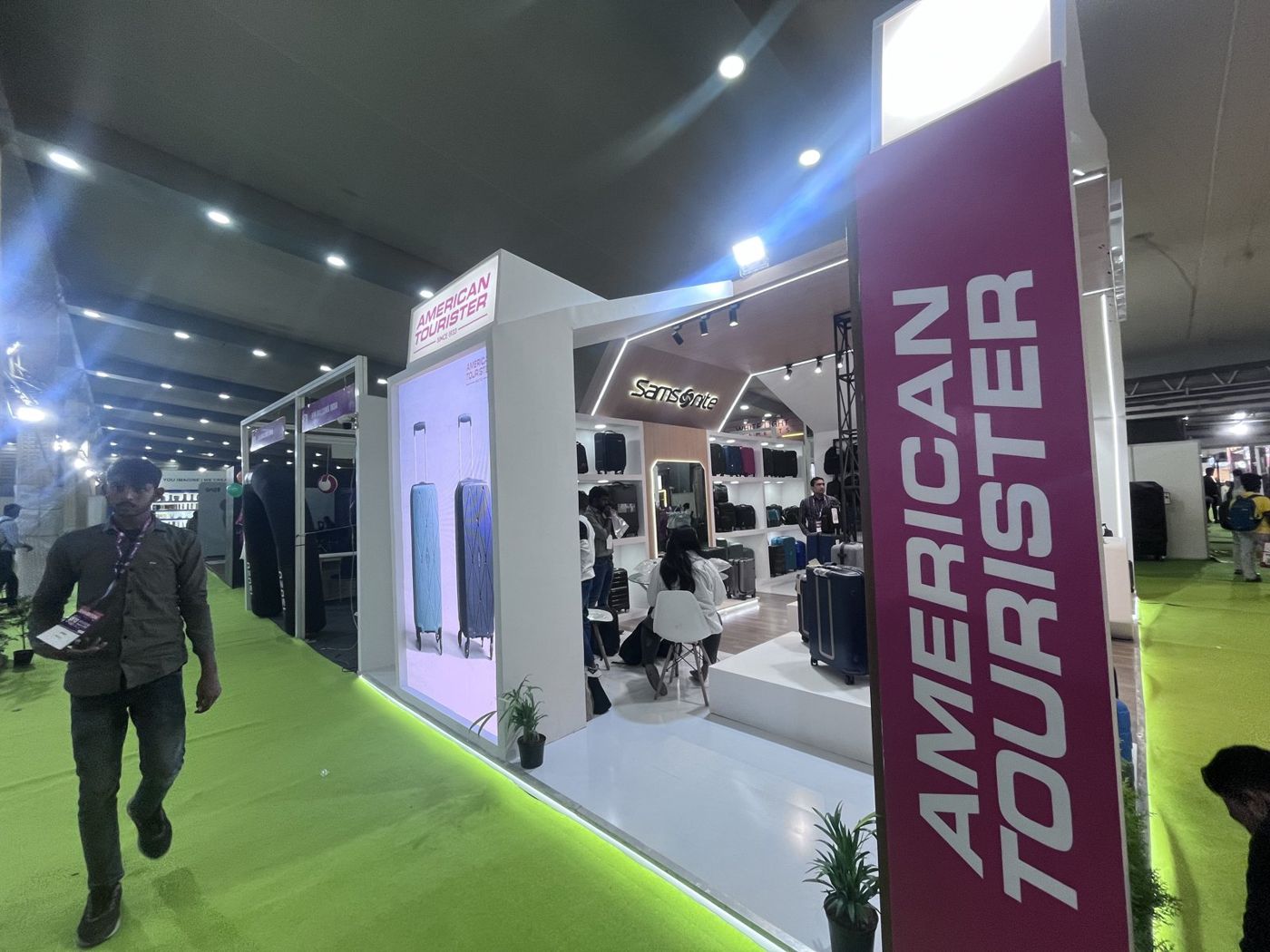 Magenta American Tourister panel and suitcase lightbox on the side of the stall