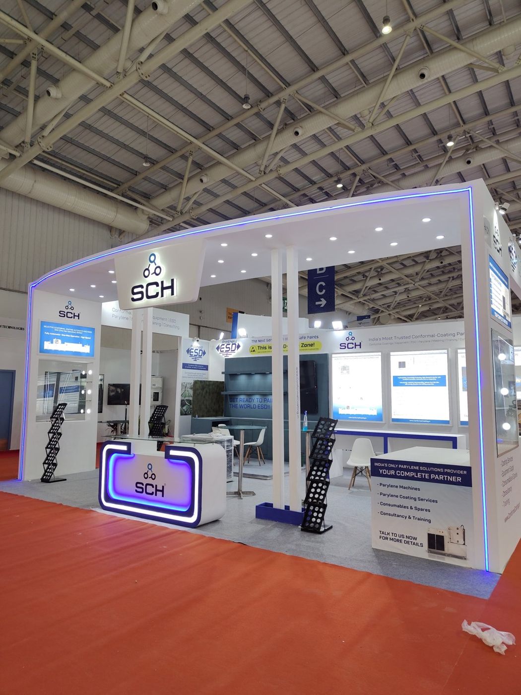 Front of the SCH stall with recessed ceiling spotlights, twin white columns and black brochure stands