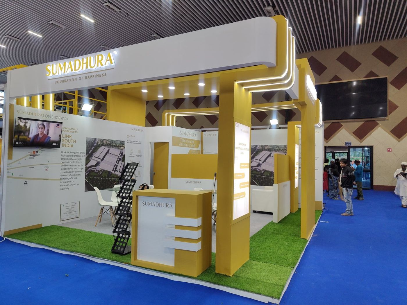 Sumadhura stall with backlit fascia letters, mustard counter with white fins and printed park graphics
