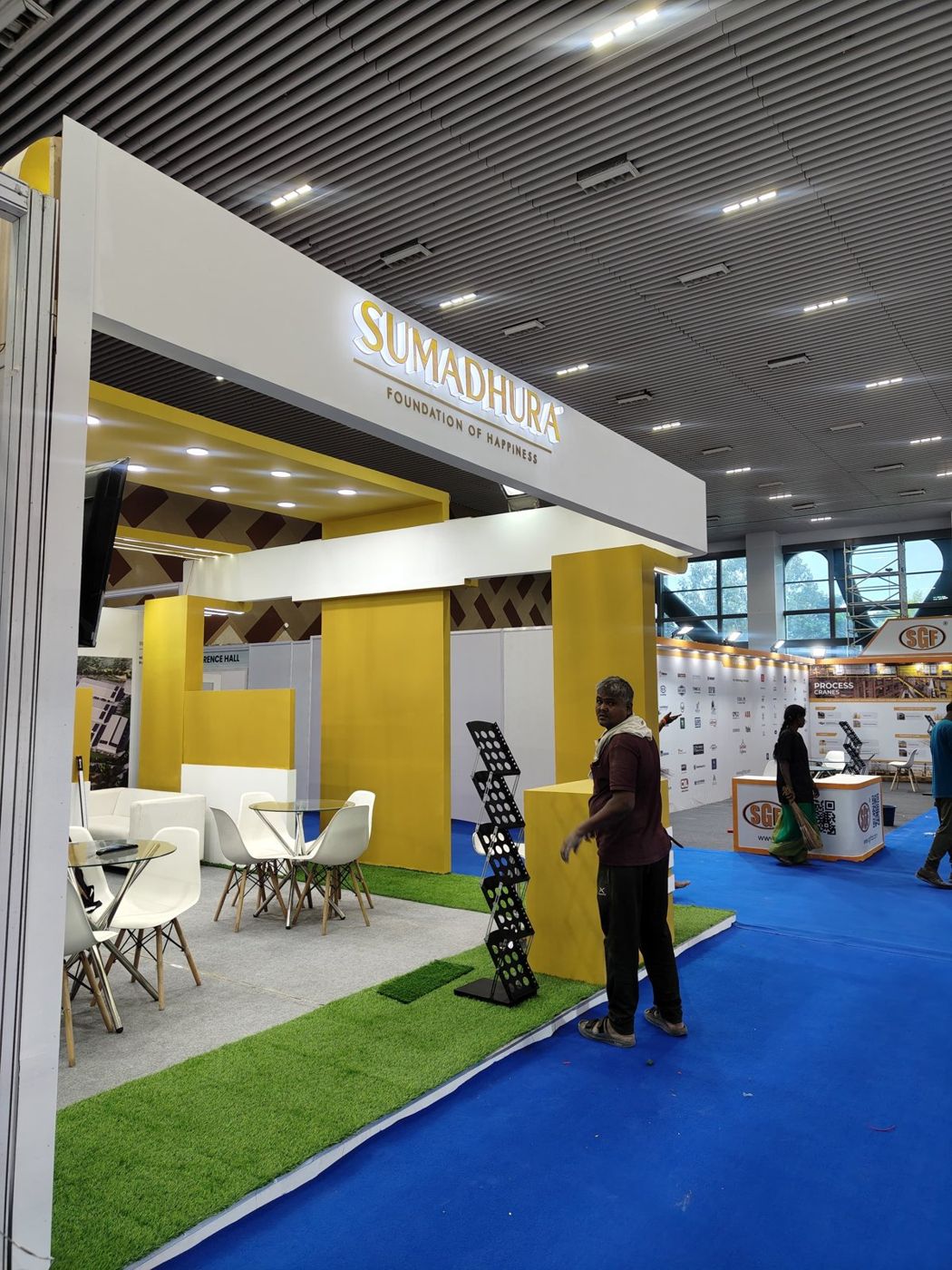 Side view of the Sumadhura stall showing the mustard ceiling frame, downlights and seating