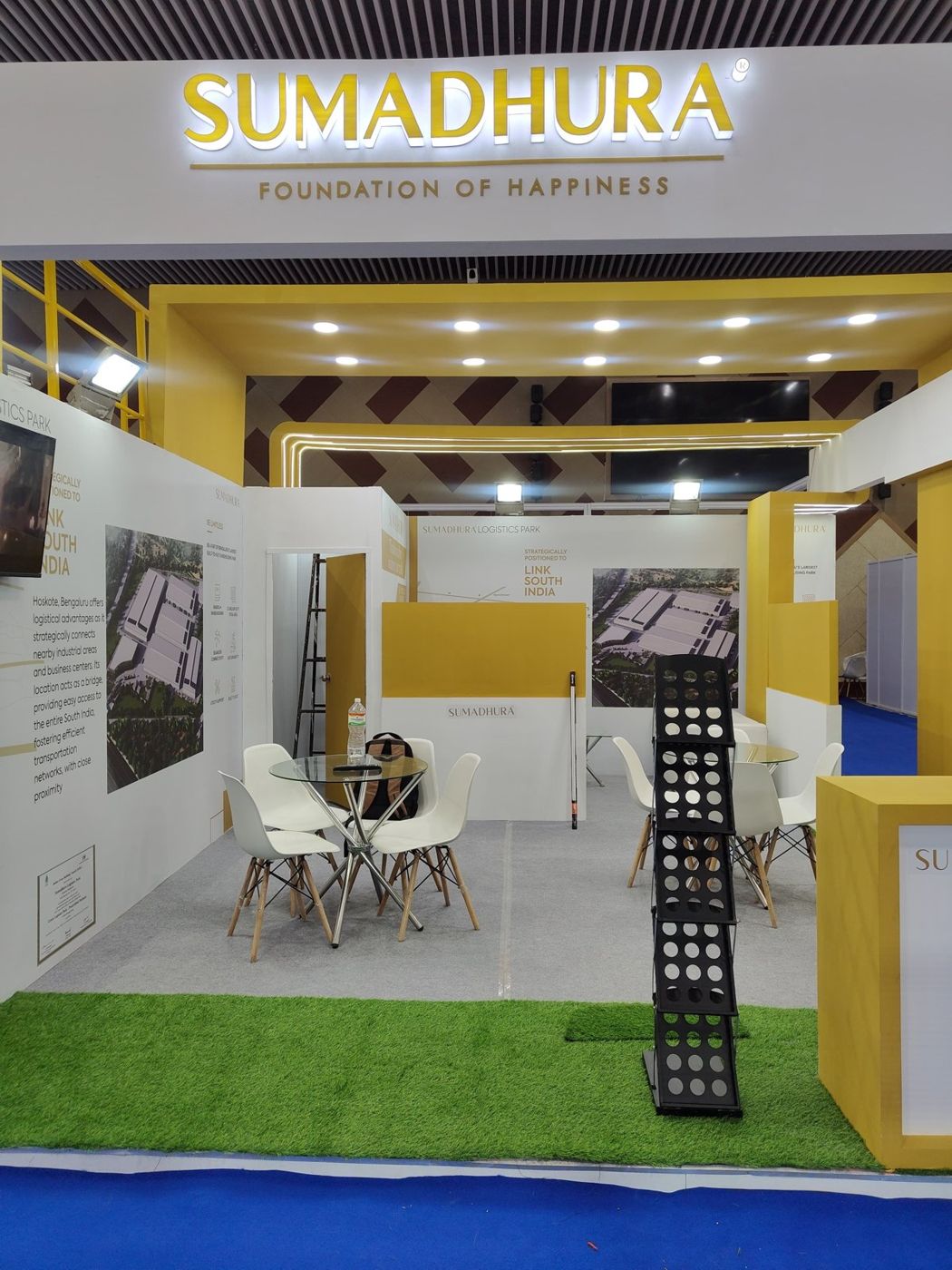 Front view into the Sumadhura stall with store room, glass tables and LED-lined back portal