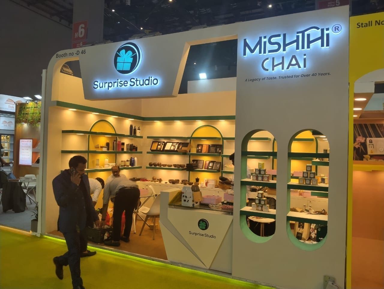Backlit Mishthi Chai lettering above oval cut-outs holding tea tins, with gift shelves inside