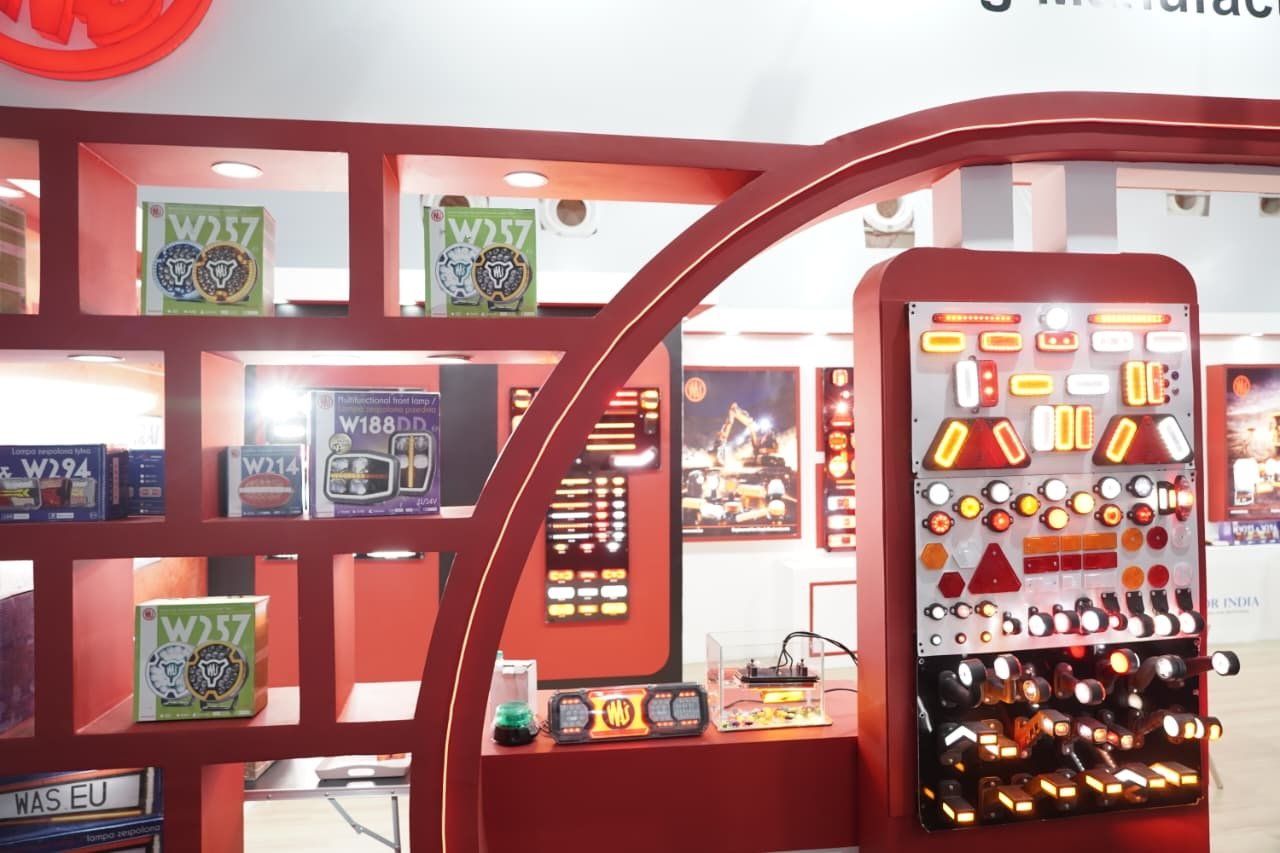 Red open cube shelves holding boxed lamps beside a wired panel of tail lamps and indicators